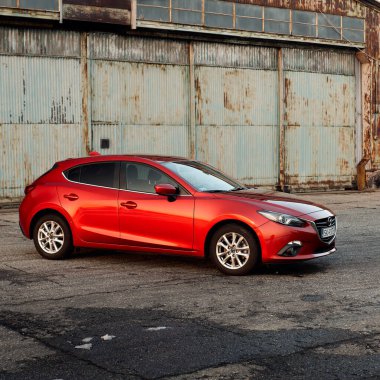 Eski bir uçak hangarının önüne park edilmiş kırmızı bir Mazda 3. Mazda 3 2013-2019 'da üretildi. Katowice - Polonya, 15 Şubat 2015