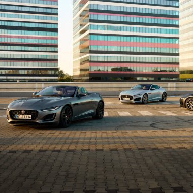 Üç Jaguar F tipi modern ofis binasının arka planında duruyor. Katowice, 17 Haziran 2022