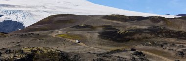 Snfellsjkull stratovolcano 'dan çakıllı bir yoldan geçen beyaz arazi Jeep Wrangler' ı. Geniş çerçeve. Snaefellsnes Yarımadası, İzlanda, 14 Ağustos 2021