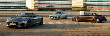 Üç Jaguar F tipi modern ofis binasının arka planında duruyor. Katowice, 17 Haziran 2022