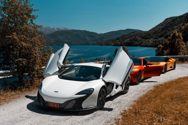 与超级汽车的公路旅行 Mclaren 650 Ferrari F12和Lamborghini Huracan停在湖边的一条砾石路上 车门开着 挪威Gransherad 2016 — 图库照片