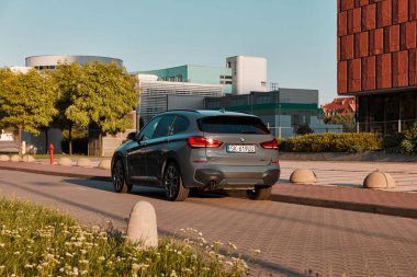 BMW X125, hibrit, fişe takılı araba, modern bir ofis binasının yanına park edilmiş. İki motorun toplam gücü 220HP. Elektrik aralığı 52 km Katowice, Poland- 07.30.2021
