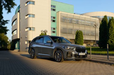 BMW X125, hibrit, fişe takılı araba, modern bir ofis binasının yanına park edilmiş. İki motorun toplam gücü 220HP. Elektrik aralığı 52 km Katowice, Poland- 07.30.2021