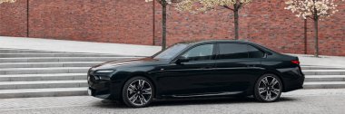 BMW 7 Serisi, G70, modern premium limuzin. Filarmoni orkestrasının arka planındaki araba. 2023 'ten beri satışta. Polonya, Katowice 03.05.2023