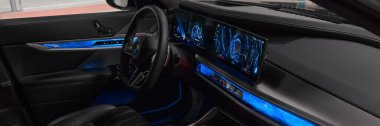 Açık yolcu kapısından bakıldığında BMW 7 serisinin mavi ışıklı iç ve ön paneli. BMW 7 Serisi, G70, modern premium limuzin. 2023 'ten beri satışta. Polonya, Katowice 03.05.2023