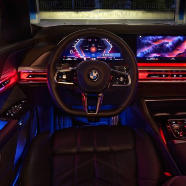 BMW 7 Serisi. Arabanın içi renklerle aydınlatılmış, direksiyonun merkezini şoförün pozisyonundan görebiliyoruz. Model G70, modern premium limuzin. 2023 'ten beri satışta. Polonya, Katowice 03.05.2023