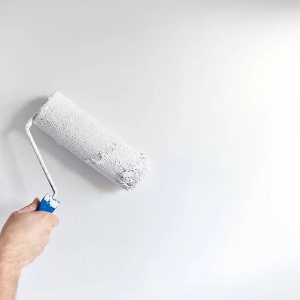 粉刷公寓 用白色油漆翻新 涂漆辊的男性手绘墙 免版税图库图片