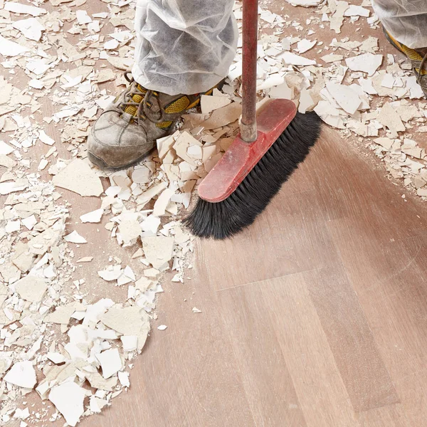 Οικοδόμος Που Σκουπίζει Πάτωμα Μετά Την Ανακαίνιση Του Σπιτιού Φωτογραφία Αρχείου