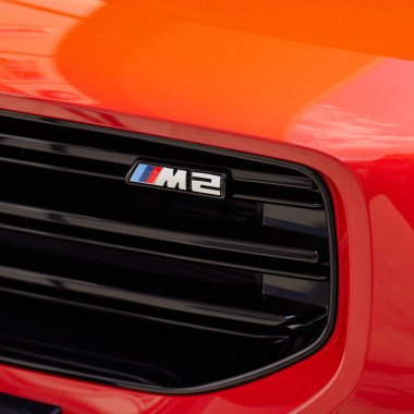 Kırmızı bir BMW 'nin radyatör ızgarasında M2 amblemi. Model G87. Motor R6, 3.0L, 460 HP, 550 Nm Katowice, Polonya, 10.06.2023