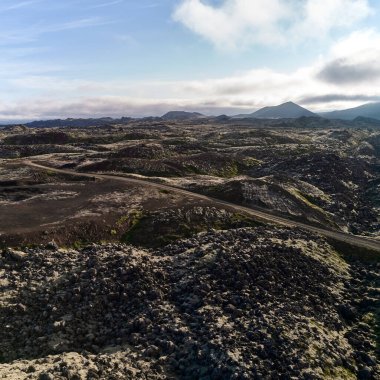Lav tarlaları arasında ufka uzanan toprak yolun manzarası. Üst görüntü, İHA 'dan çekilen fotoğraf. Helgafelveit, İzlanda.