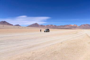 Bolivya, Salvador Dali Çölü. Nissan Devriyesi ve çölün ortasında duran bir adam. Boliwia, Avoroa Ulusal Parkı, 14.10.2023