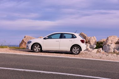 Volkswagen Polo yolun kenarında manzaralı bir yere park etmiş. Adanın etrafındaki bir kiralama şirketinden Volkswagen Polo ile gezintiye çıkmış. Brac Adası, Hırvatistan, 05.25.2019