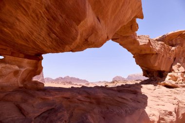 Wadi Rum Çölü 'nde doğal kaya kemeri oluşumu, Jordan. Rüzgâr erozyonunun oyduğu antik kumtaşı köprüsü dramatik çöl manzarası ve dağlar.