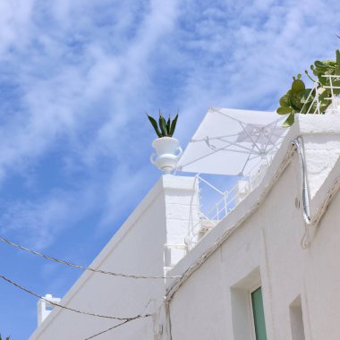 Beyaz Akdeniz mimarisi dekoratif balkonlu ve kaktüslü Monopoli 'de parlak mavi gökyüzüne karşı. Asılı kablolarla geleneksel İtalyan kentsel detayları