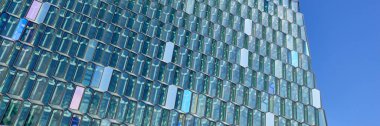 Reykjavik, İzlanda 'daki Harpa Konser Salonu' nun mimari detayları. Gökyüzünü yansıtan geometrik desenli cam cephe. Modern mimari ve kültürel dönüm noktası.