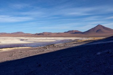 Bolivya 'daki Avaroa Ulusal Parkı' nın engin arazisi kuru göl yatakları, renkli mineral yatakları ve dağınık bulutlu mavi gökyüzünün altındaki uzak dağların çarpıcı manzarasını ortaya çıkarıyor..