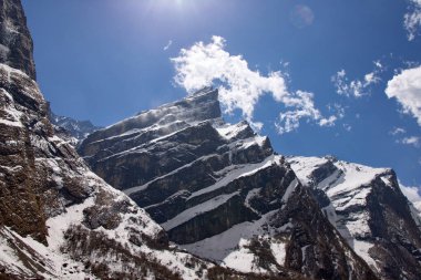 Karla kaplı dağlar Annapurna bölgesinde canlı, mavi bir gökyüzüne karşı çarpıcı bir şekilde yükselir. Bu nefes kesici manzara Nepal 'in görkemli manzarasındaki yürüyüşün özünü yakalar.