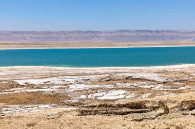 Ziyaretçiler Ürdün 'deki Ölü Deniz' in çarpıcı mavi sularına hayran. Kurak manzaralar ve temiz bir gökyüzü altında tuz oluşumları dinlenmek ve keşfetmek için mükemmel.