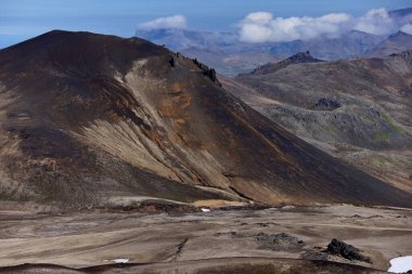 İzlanda. Uçsuz bucaksız Snaefellsjokull manzaraları parlak mavi gökyüzünün altında kayalık arazinin ve kar parçalarının çarpıcı bir tezatını gözler önüne seriyor, İzlanda 'nın eşsiz jeolojik özelliklerini gözler önüne seriyor.