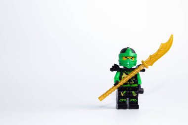 LEGO Ninjago Lloyd karakteri beyaz arka plana karşı iki eli kılıçlı