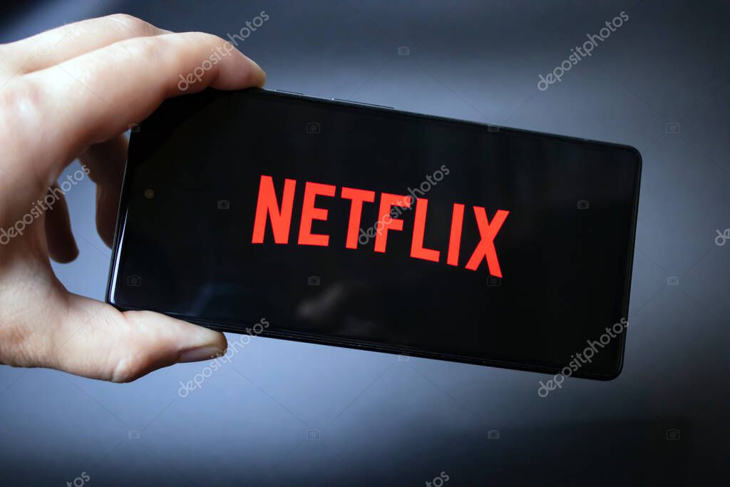 Hand holding a smartphone with the Netflix logo on it