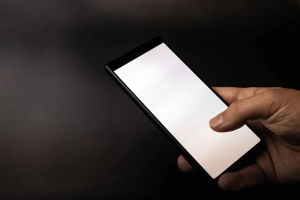 Gri siyah arka planda beyaz ekranlı akıllı telefonu tutan bir el.