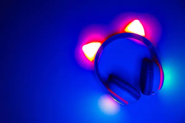 Koyu mavi arka planda neon ışıkları olan çocukların kablosuz kulaklıkları.