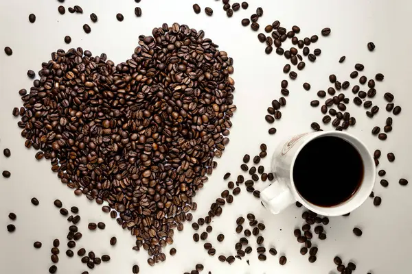 coffee beans in the shape of heart, a cup of coffee