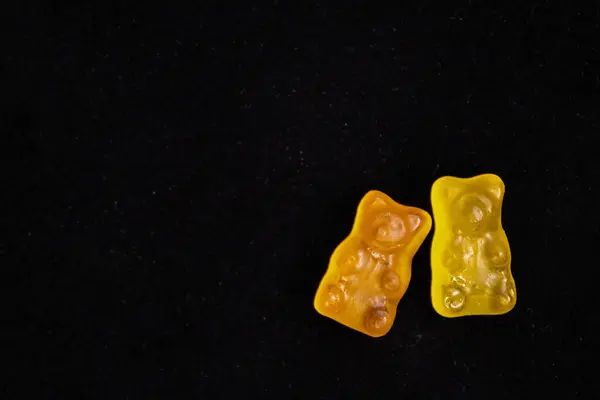 İki parlak renkli jelibon ayıcığı koyu bir arka planda