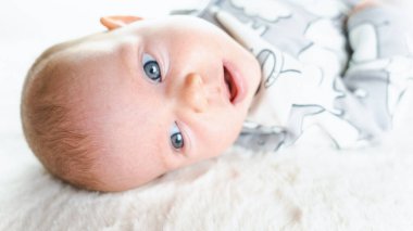 Yeni doğmuş bebek afişi. Beyaz yatakta yatan mutlu, tatlı bir kız bebek. Yatakta yatan sevimli küçük çocuk. Çocukluk banyosu kavramı