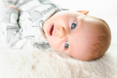 Bebek yalancı çocuk afişi. Beyaz yatakta yatan mutlu, tatlı bir kız bebek. Yatakta yatan sevimli küçük çocuk. Çocukluk banyosu kavramı