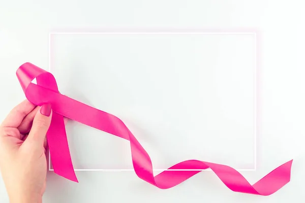 Pink ribbon background. Health care symbol pink ribbon in woman hands on white background. Breast cancer support concept. World cancer day