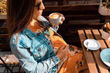 Hamile kadın kahve içer. Hamilelik sabahı mutlu bir kızla espresso kahvesi içmek. Kahve ürünü reklamı kavramı