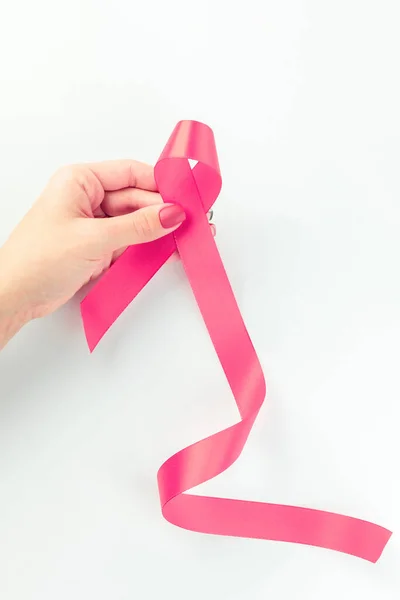 Cancer awareness. Health care symbol pink ribbon in woman hands on white background. Breast woman support concept. World cancer day