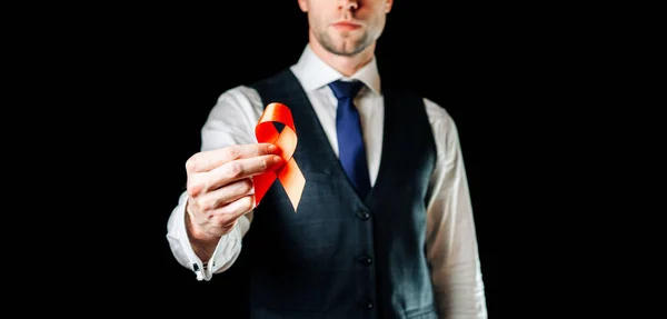 Hiv aids. Red ribbon in hiv world day isolated on dark background. Man holding awareness aids and cancer symbol. Health, Medical sign. copy space