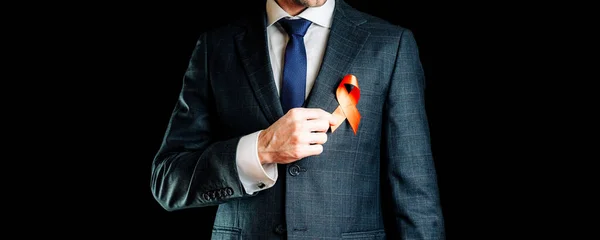 Aid ribbon silk. Red ribbon in hiv world day in man hand. Awareness aids and cancer symbol on black background. HIV, AIDS and aging awareness month with copy space