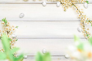 Paskalya beyaz arka planı. Bahar çiçeği sınırı, beyaz mutlu paskalya yumurtası ahşap bahar arka planında. Paskalya kartı. Düz yatıyordu