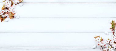 Paskalya beyaz arka planı. Bahar çiçeği sınırı, beyaz mutlu paskalya yumurtası ahşap bahar arka planında. Paskalya kartı. Düz yatıyordu