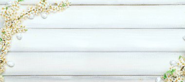 Paskalya beyaz arka planı. Bahar çiçeği sınırı, beyaz mutlu paskalya yumurtası ahşap bahar arka planında. Paskalya kartı. Düz yatıyordu