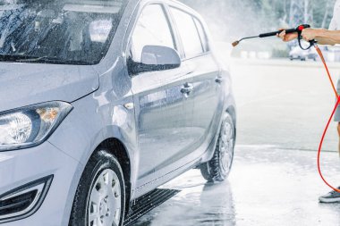 Adam arabayı temizliyor. Sprey hortum köpük sabunu. Araba yıkama suyu dış görünüşü parlatır.
