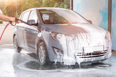Adam arabayı temizliyor. Sprey hortum köpük sabunu. Araba yıkama suyu dış görünüşü parlatır.