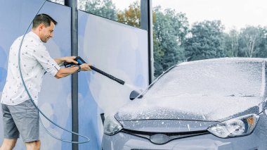 Araba yıkama köpükleri. Sabun köpüğü su sıçraması. Aracın dışı ıslak ve parlak.