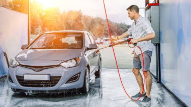 Araba temizliği. Adam arabayı spreyle yıkıyor. Köpüklü su sabunu servisi.