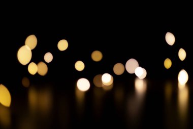 Bokeh altın parlak ışıklar. Siyah bir arka planda Noel süsünün bulanık ışıkları