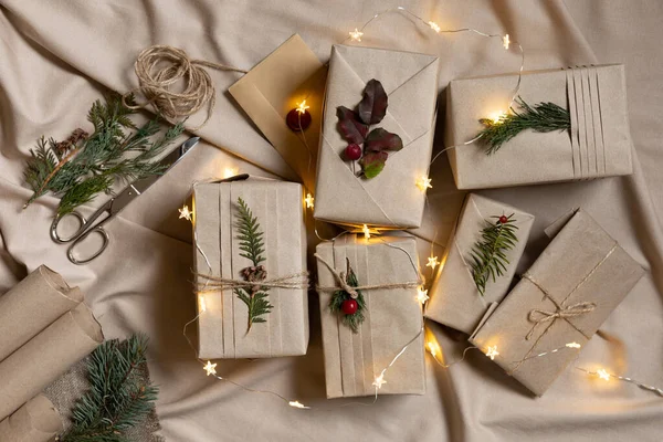 许多圣诞礼品盒 环保包装风格 带有时髦褶皱和天然枝条的牛皮纸 经典剪子 亚麻织物 — 图库照片