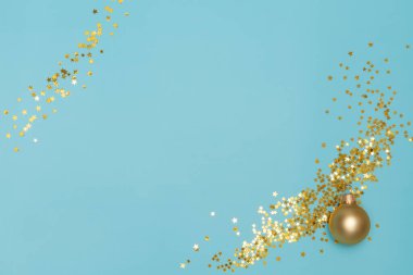 Matte Golden Christmas balosu ve parlak mavi arka planda yıldız şeklinde konfeti. Parlak pullar. Uzayı kopyala Düz yatıyordu