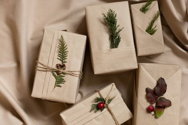 圣诞礼品盒 时尚和服风格与环保材料 亚麻纺织品背景上有褶皱 天然枝条和浆果的牛皮纸 — 图库照片