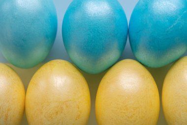 Kağıt arka planda paskalya sarısı ve mavi yumurtalar. Düz yatış, üst görünüm