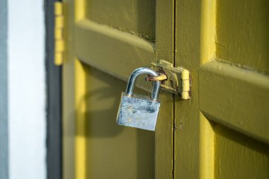 Yellow wood door closed with rusty padlock. Security concept.
