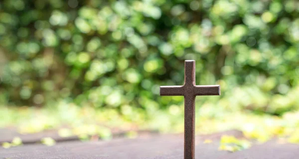 Cross with green bokeh nature background. Good Friday or christianity concept.